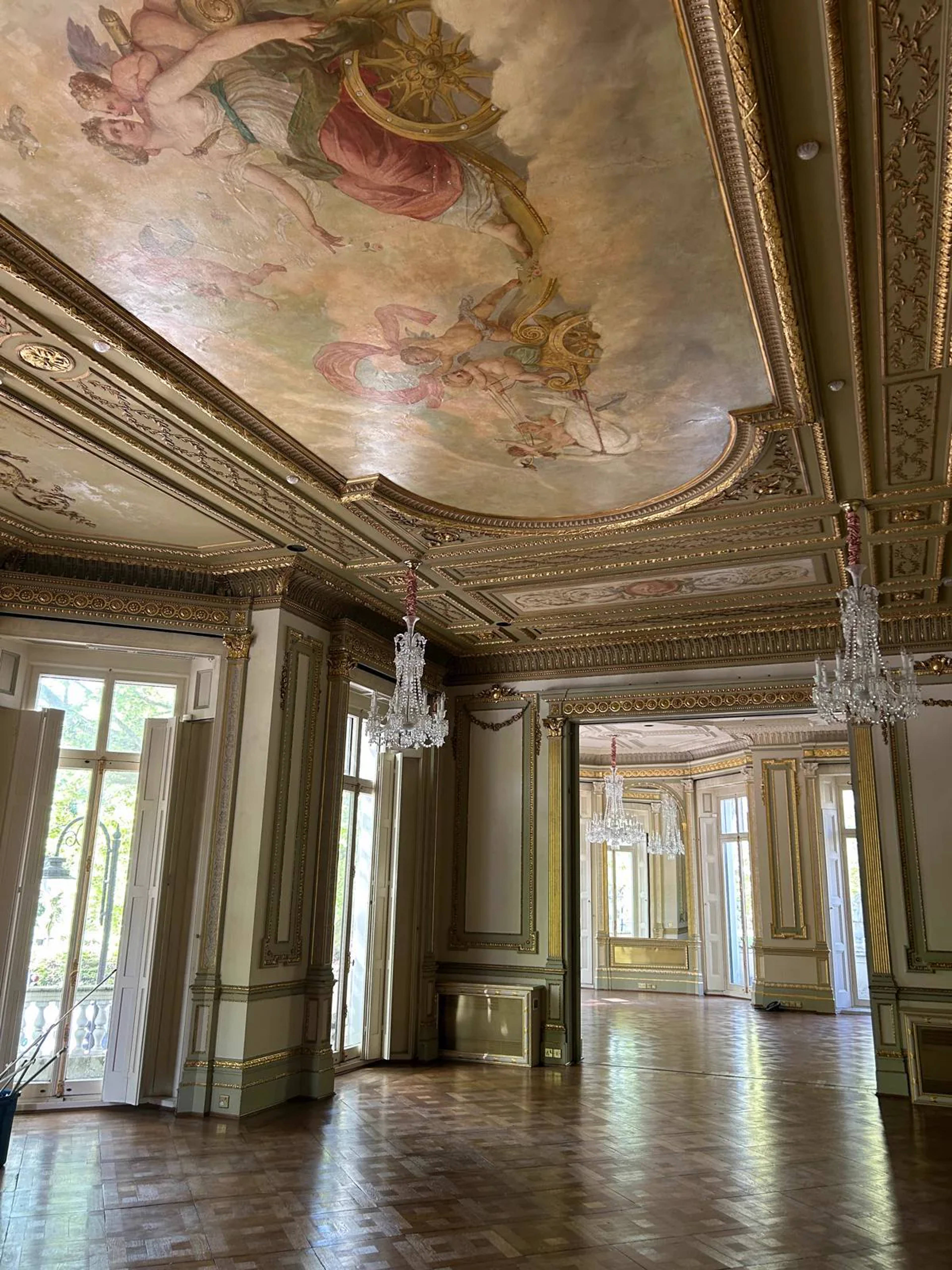 An ornate gilded reception room with a painted ceiling