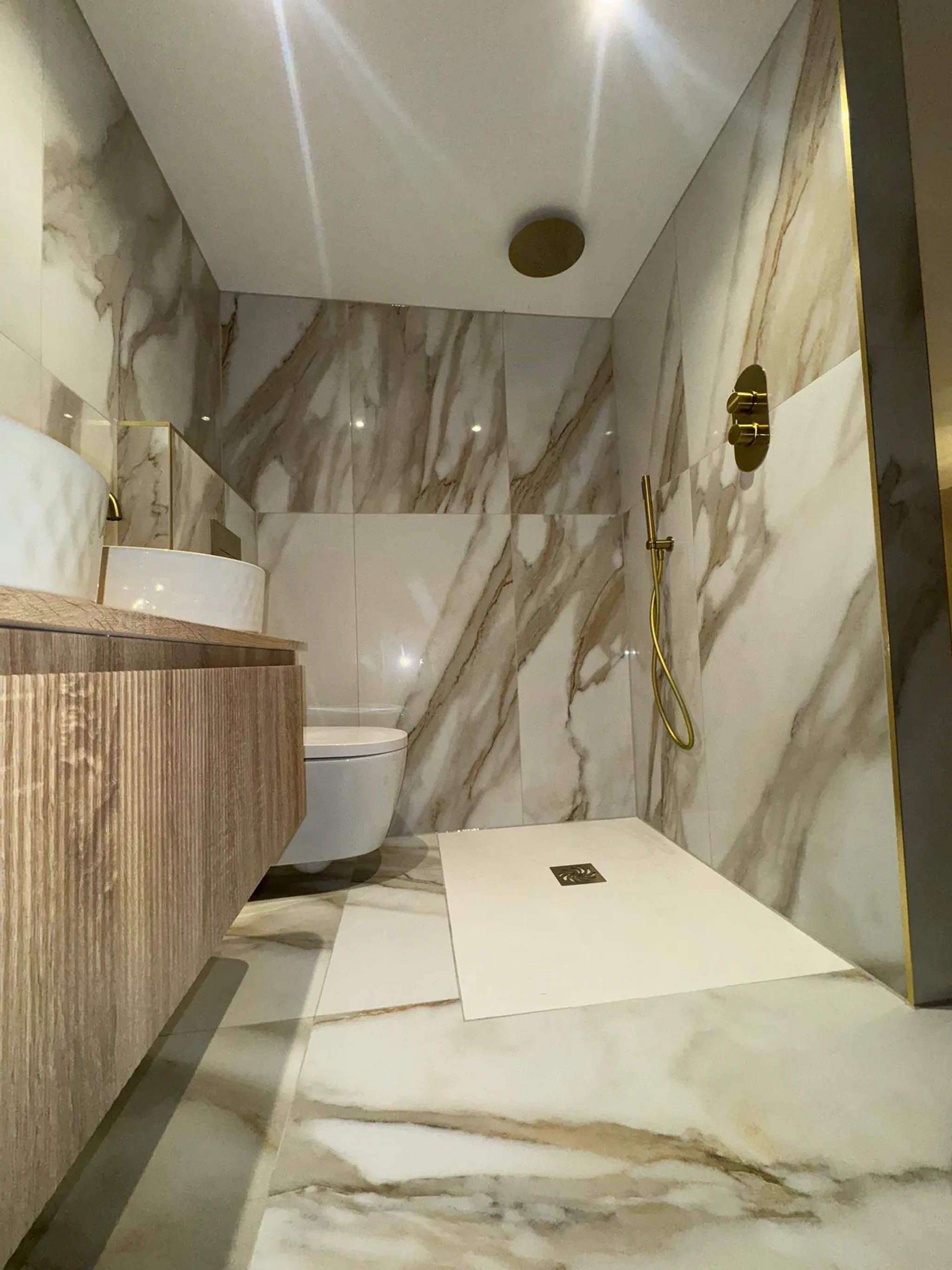 Marble wet room with brass shower fittings, fluted oak vanity and wall-hung WC