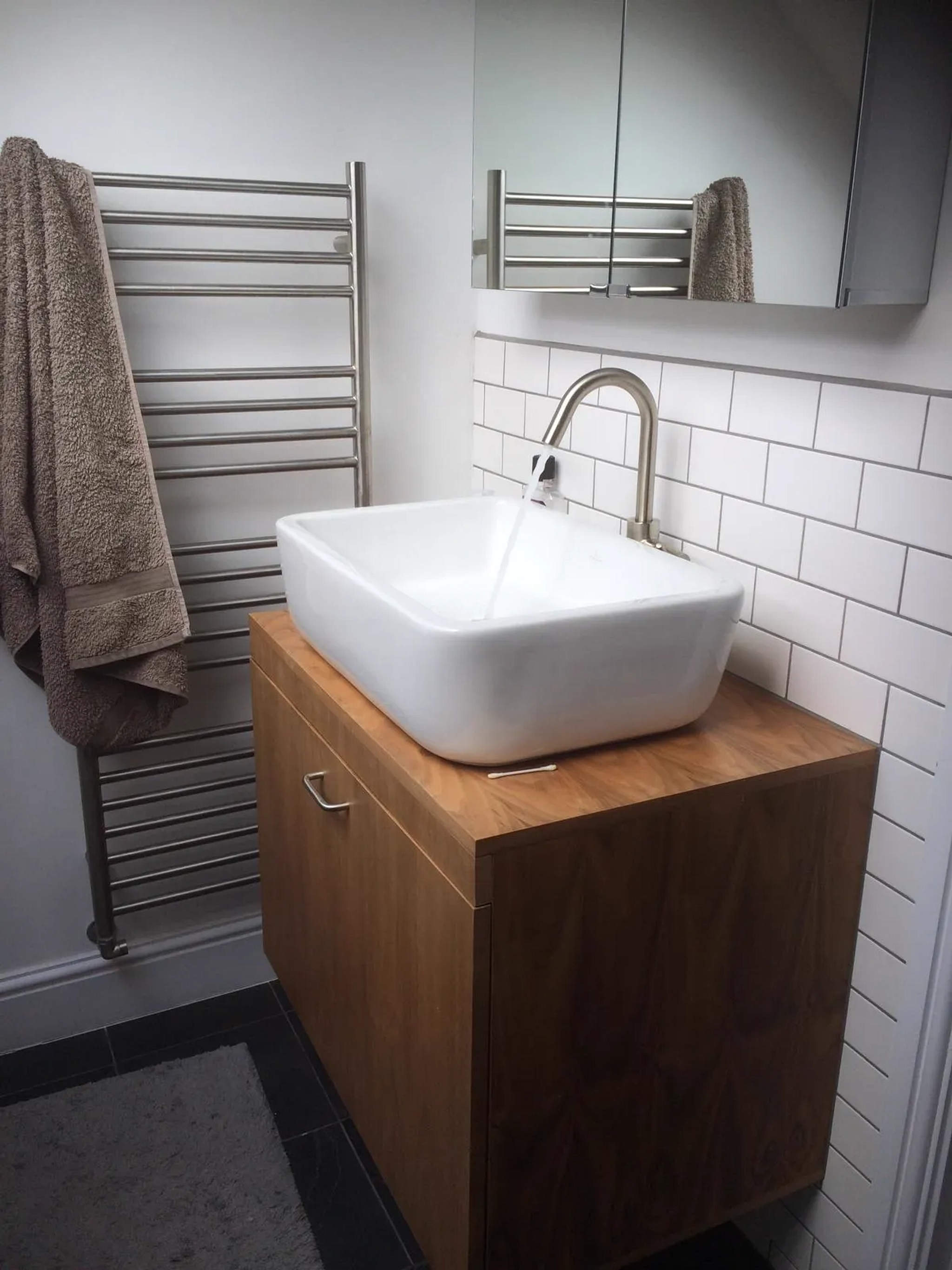 Square white vessel basin on oak vanity with metro tiling and brushed steel heated towel rail