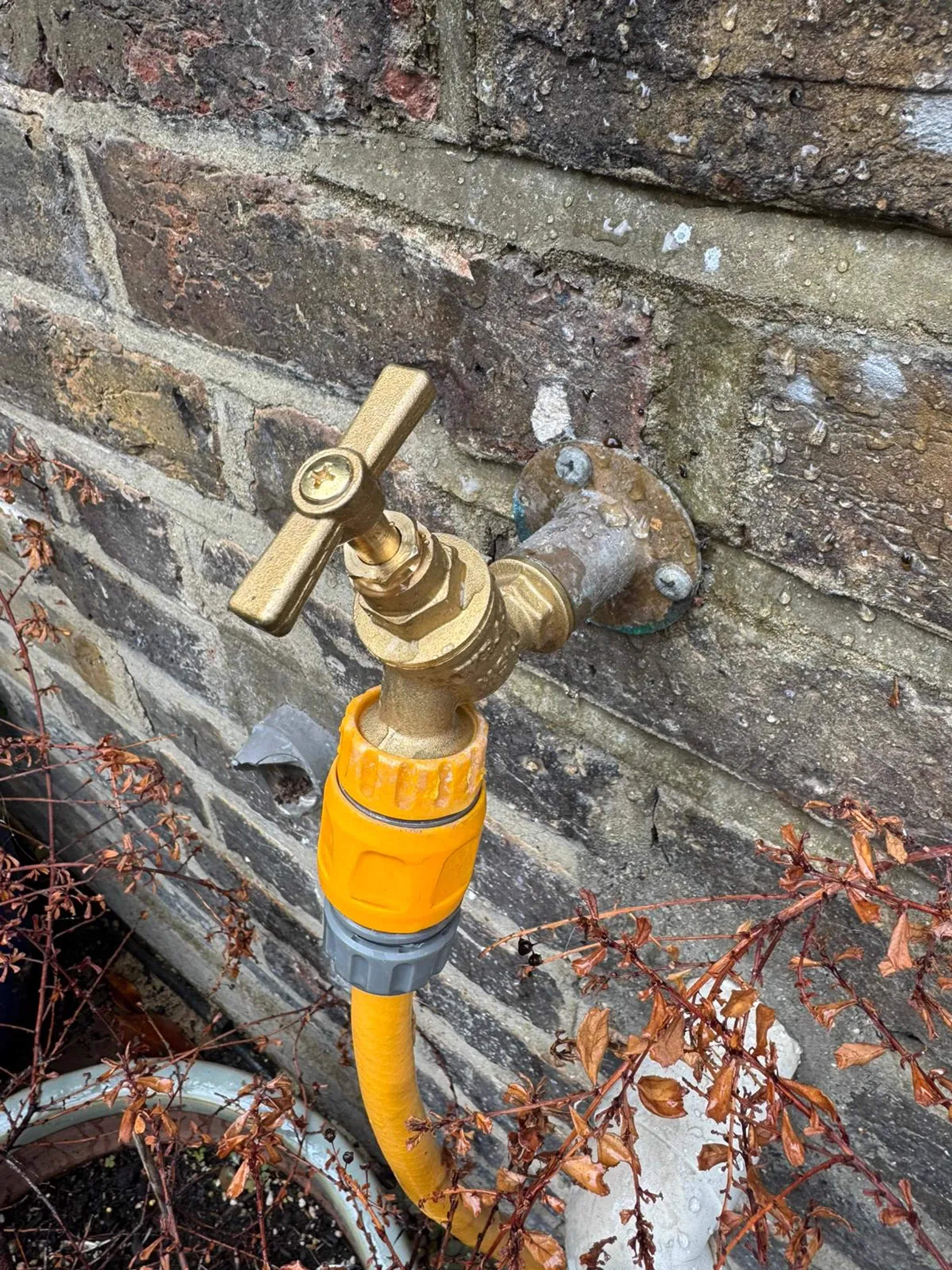 Brass outside tap with hose connector fitted to a brick wall for external water supply