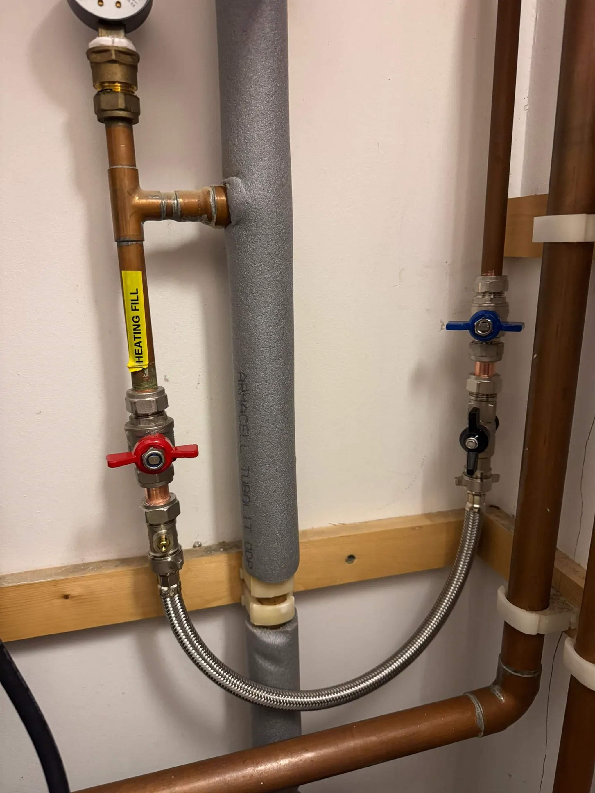 Heating fill loop with red and blue lever valves and braided hose on copper pipework