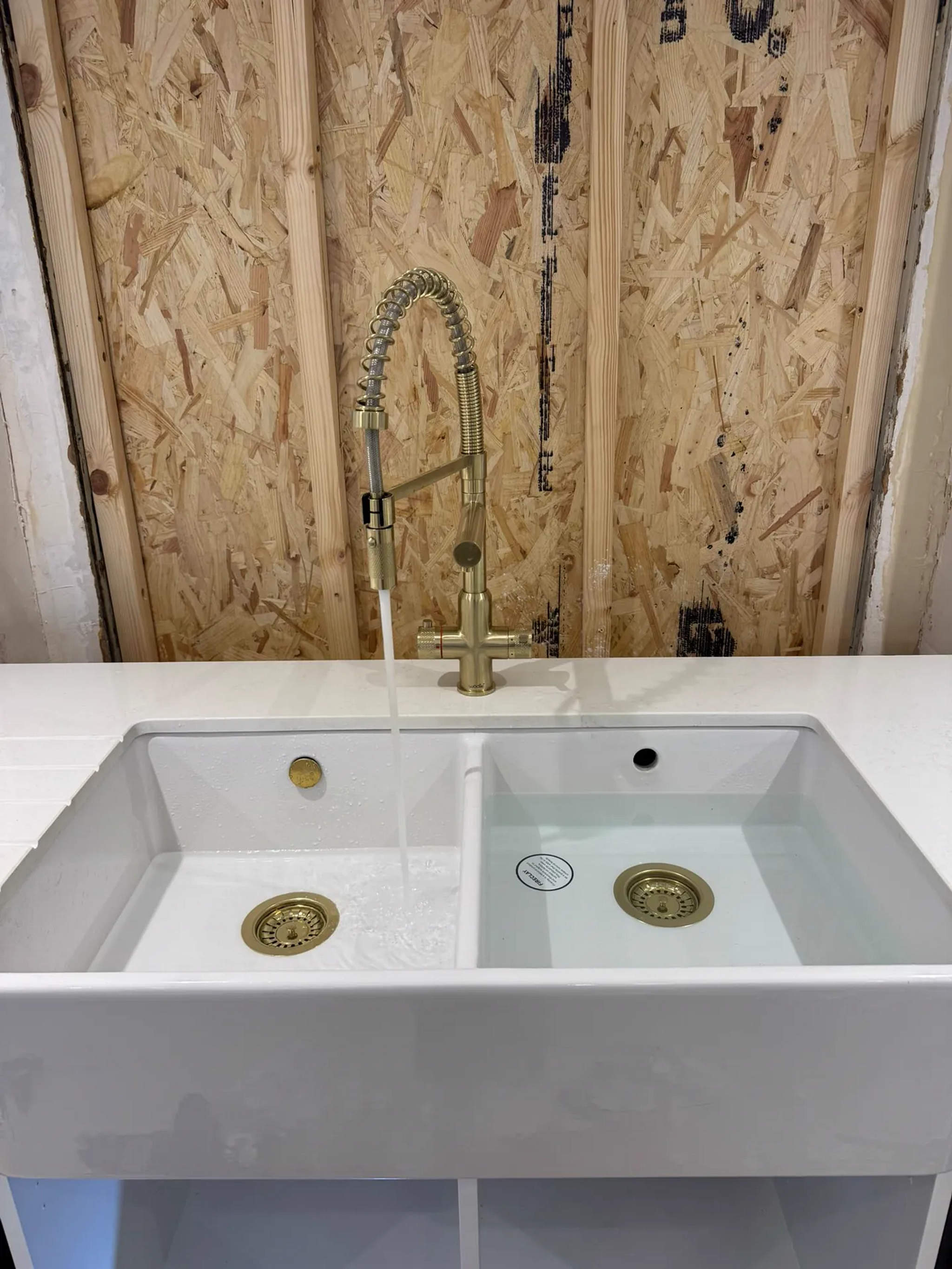 White double Belfast sink with brushed gold spring kitchen tap running into the bowl
