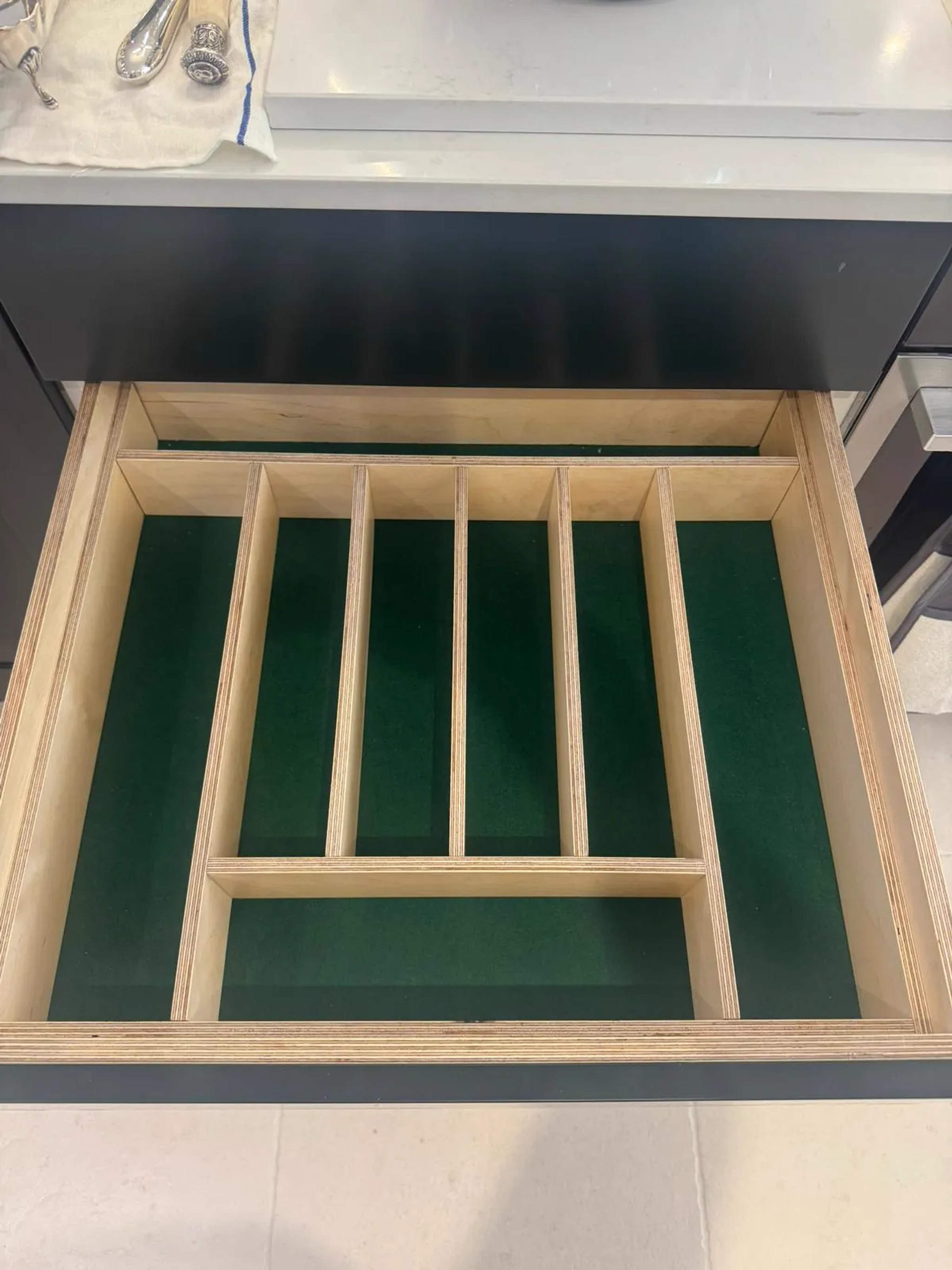 Birch plywood cutlery drawer insert with green felt lining in a kitchen unit