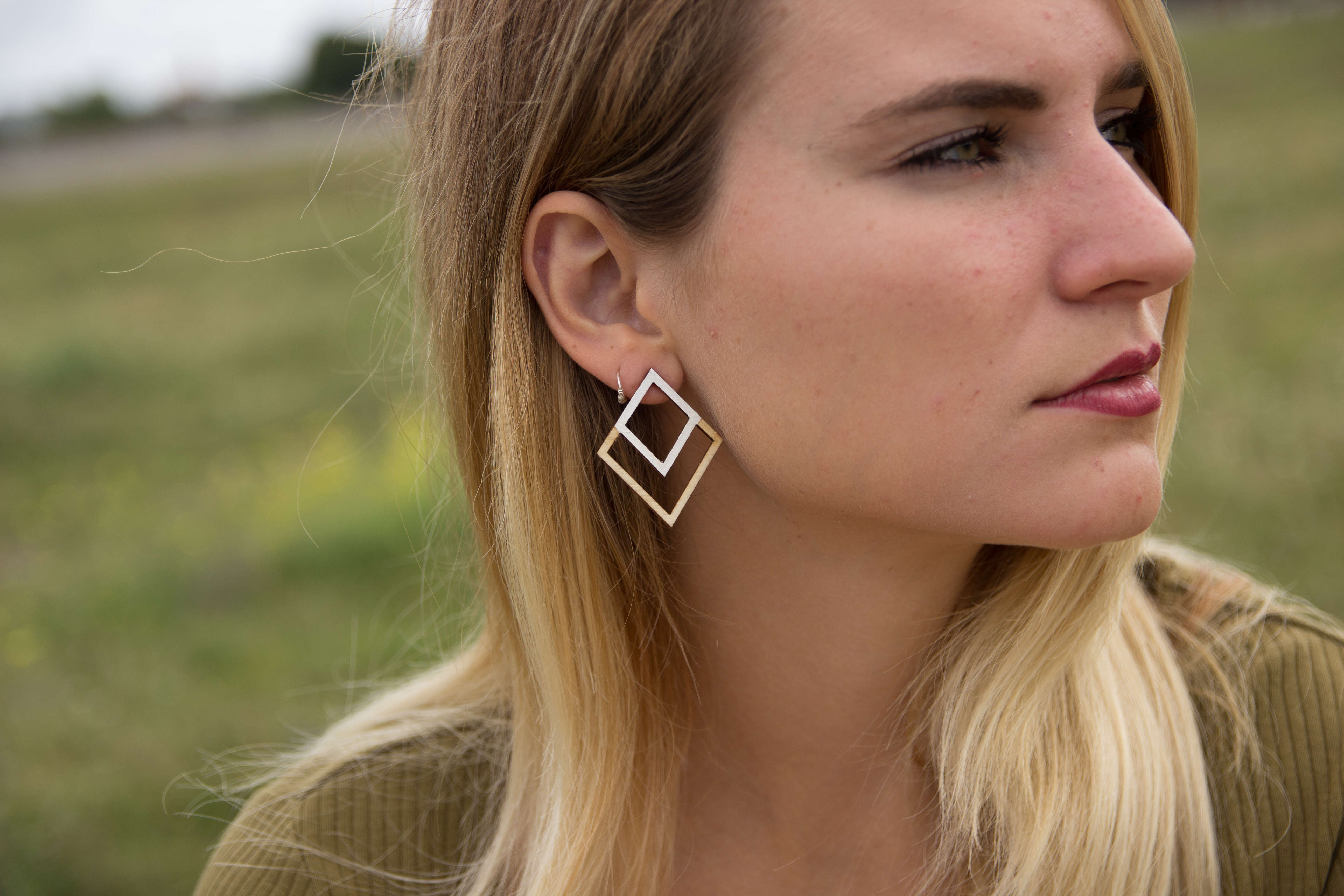 a woman wearing a earring comprised of two overlapping squares, one double the size of the other