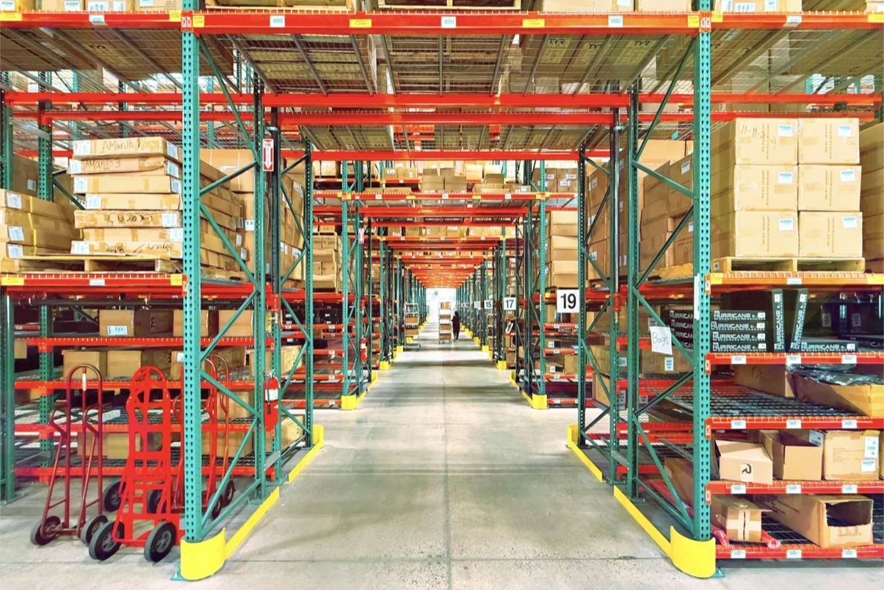 A warehouse aisle between tall racks of stacked pallets