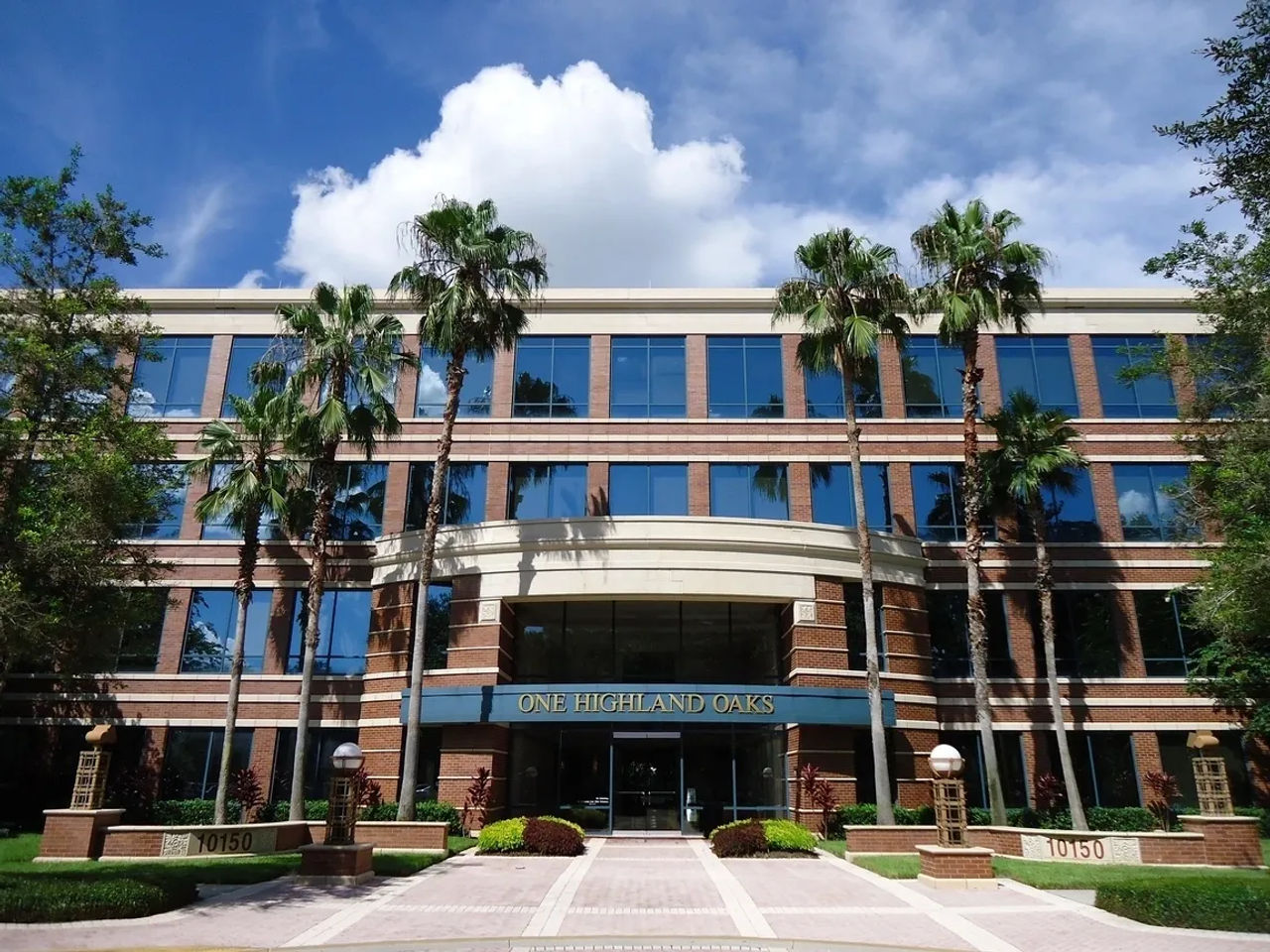 Office building entrance framed by palm trees under a bright Florida sky
