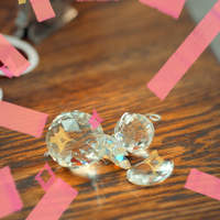 Photo of sparkling cut-glass jewels on a wooden table with pink graphic accents.