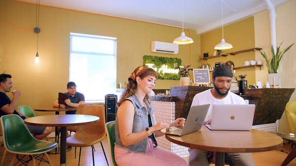 People working on laptops while sitting at cafe table