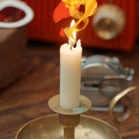 Photo of a lit candle in a brass holder with a glowing flame.