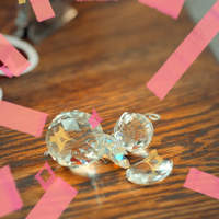 Photo of sparkling cut-glass jewels on a wooden table with pink graphic accents.
