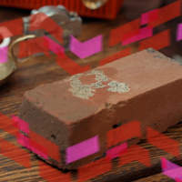 Photo of a clay brick on a wooden table with pink and red graphic accents.