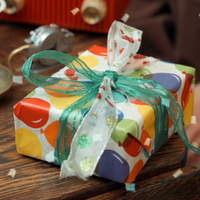 Photo of a gift wrapped in colorful paper with a bow on a wooden table.