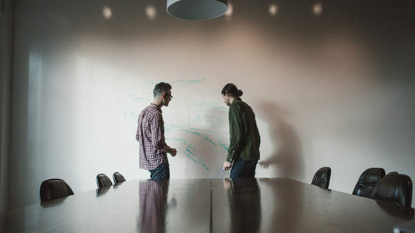 Jon Collins and Tim Mackie standing at a whiteboard.