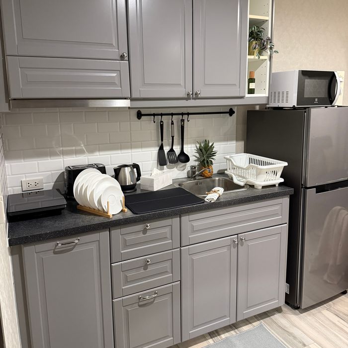 Kitchen with induction cooktop, fridge, microwave, built-in cabinets, cookware