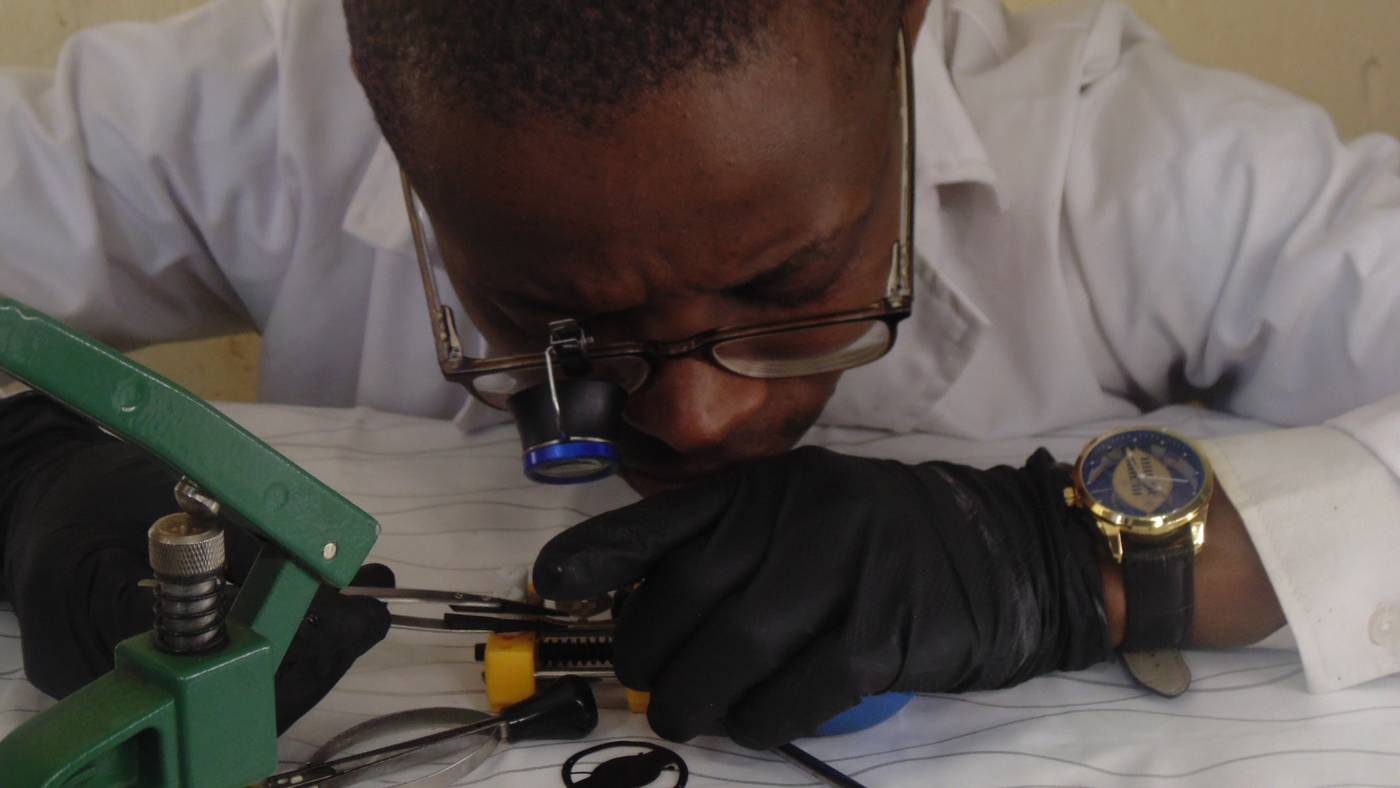 Sakhile assembling a watch under a loupe in the workshop
