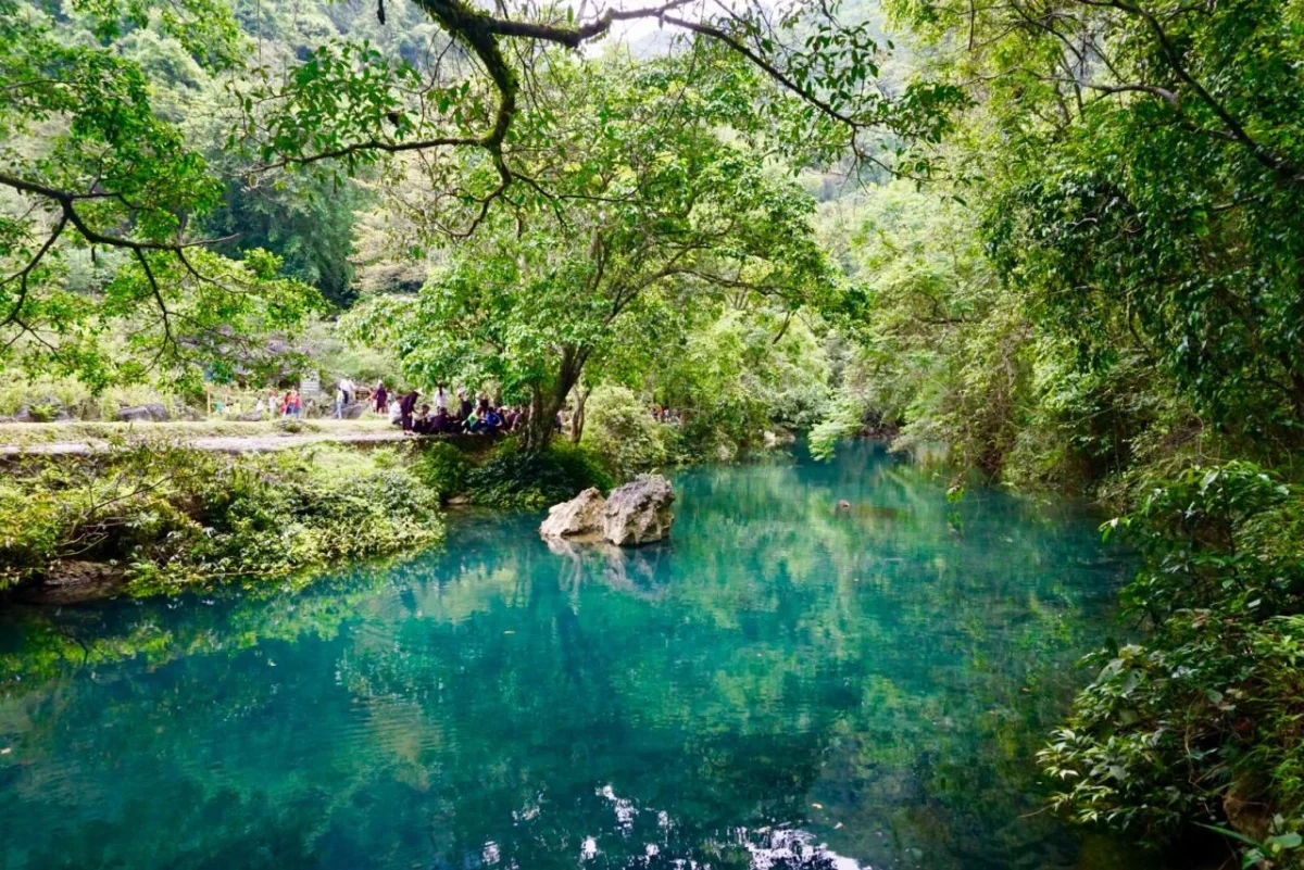 Le Nin Stream with crystal-clear emerald water reflecting the sky and mountains