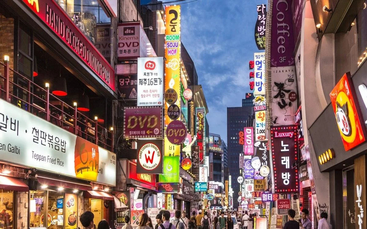 Myeongdong at night glowing with decorative lights and bustling shoppers.