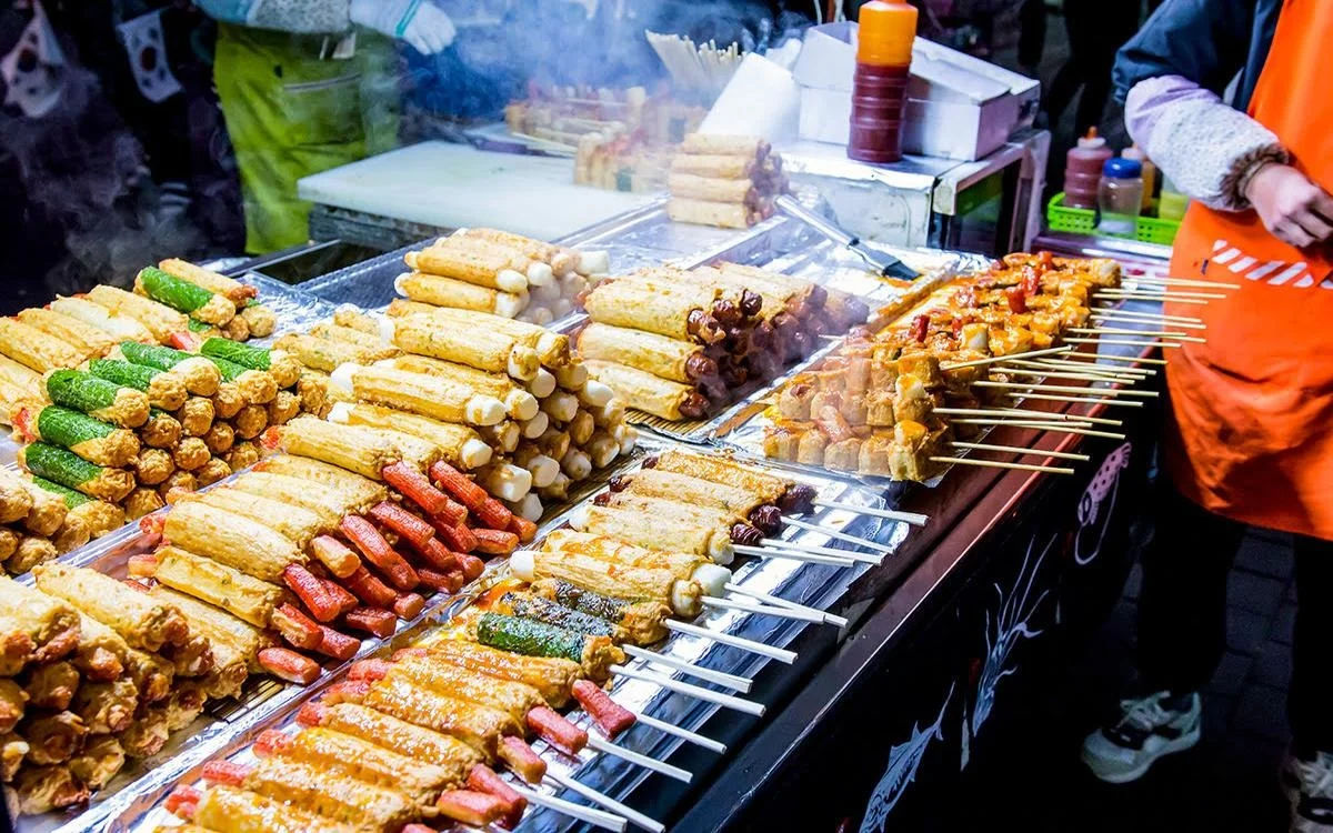 Fried fish cake stall featuring various skewers, rolls, balls, and sliced fish cakes.