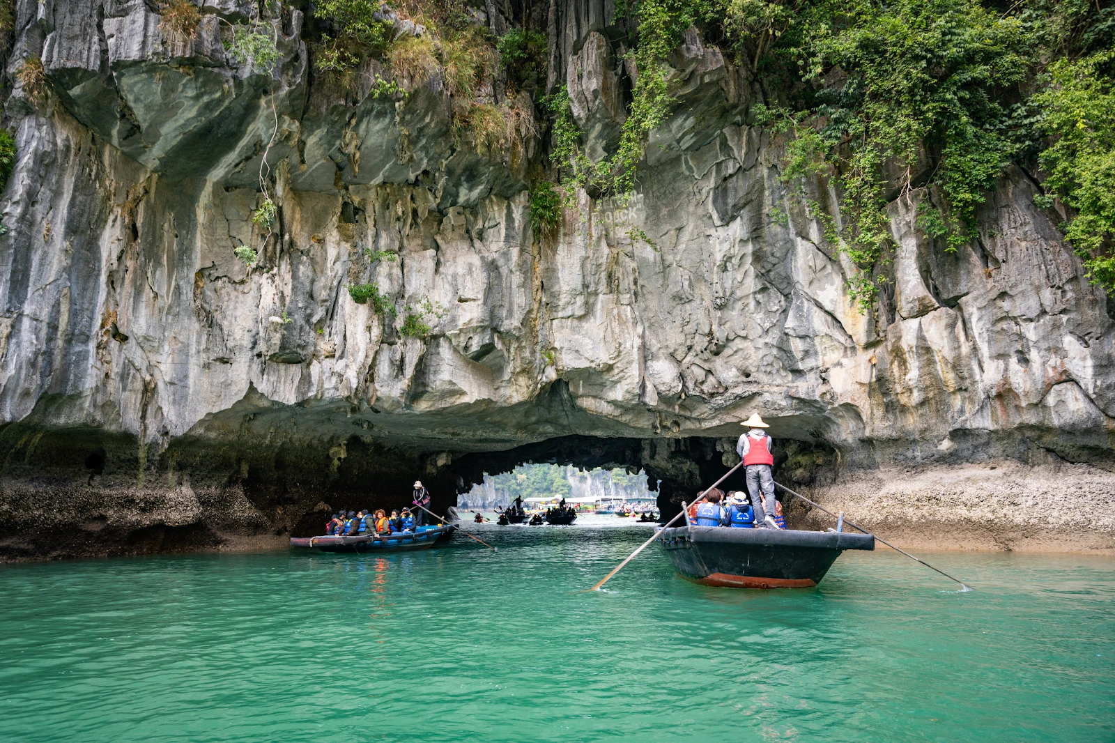Entrance to Luon Cave in Ha Long Bay with a natural stone arch and emerald water inside