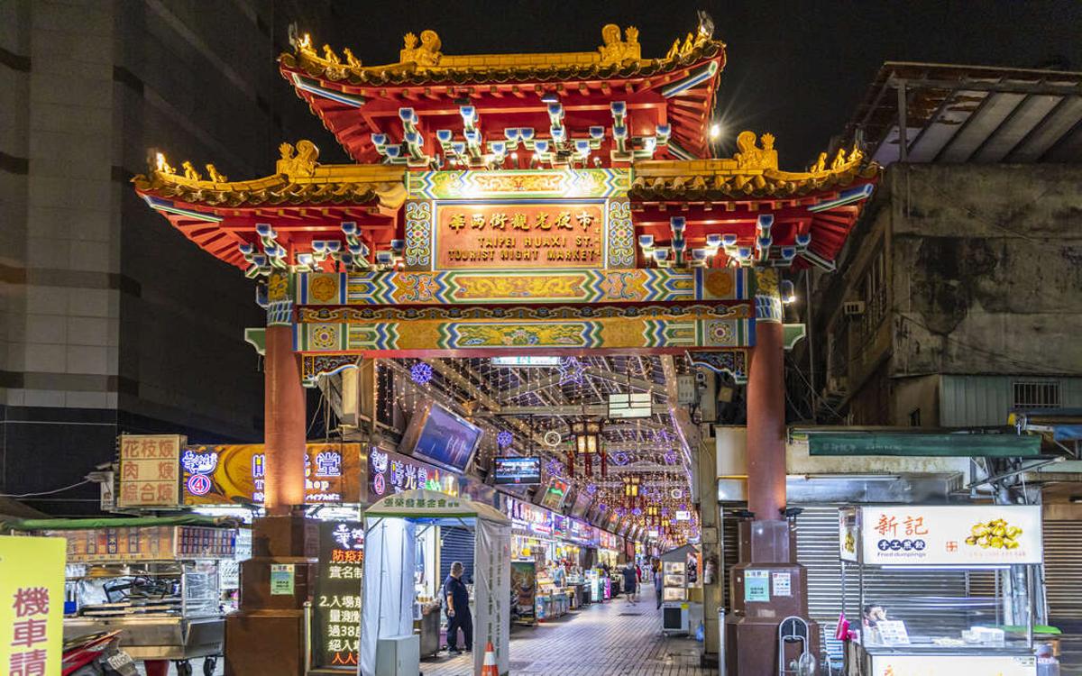 The entrance to Huaxi Night Market features traditional tiled roofs and dazzling lights.