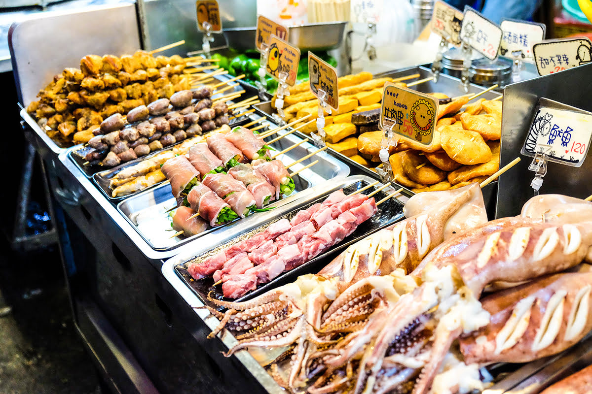 Street food stalls at Taipei night markets featuring grilled skewers, seafood, and fried snacks.