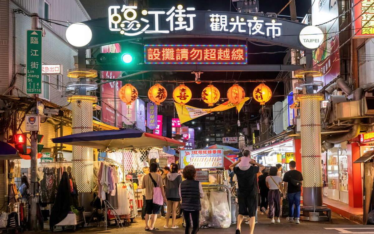 The entrance to the Linjiang night market was brightly lit with hanging lanterns, and many people strolled below.