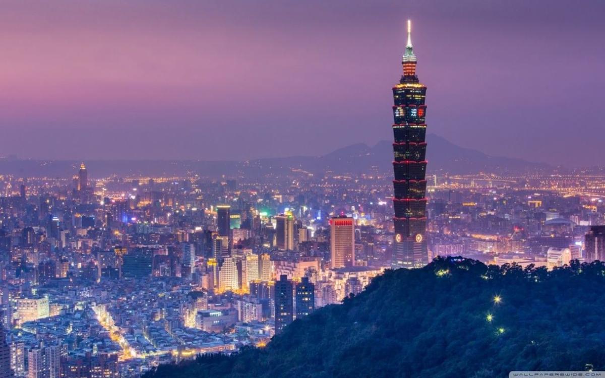Taipei 101, a towering landmark in the city, is seen from a tree-covered hillside.