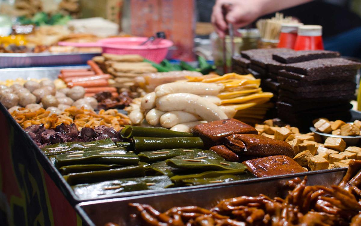 The food stalls at the night market offer a variety of items such as sausages, seaweed, tofu, and pre-cooked offal.