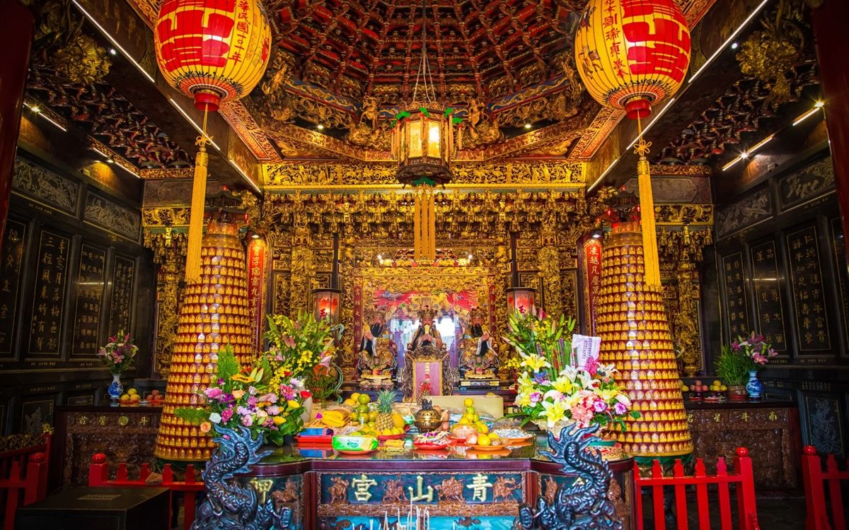 Hình ảnh nội điện Chùa Thanh Sơn với trần chạm trổ vàng rực, đèn lồng đỏ, tháp nến lớn và bàn thờ nhiều lễ vật