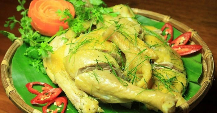 Whole boiled Tien Yen hill chicken with glossy golden skin, presented on a bamboo tray