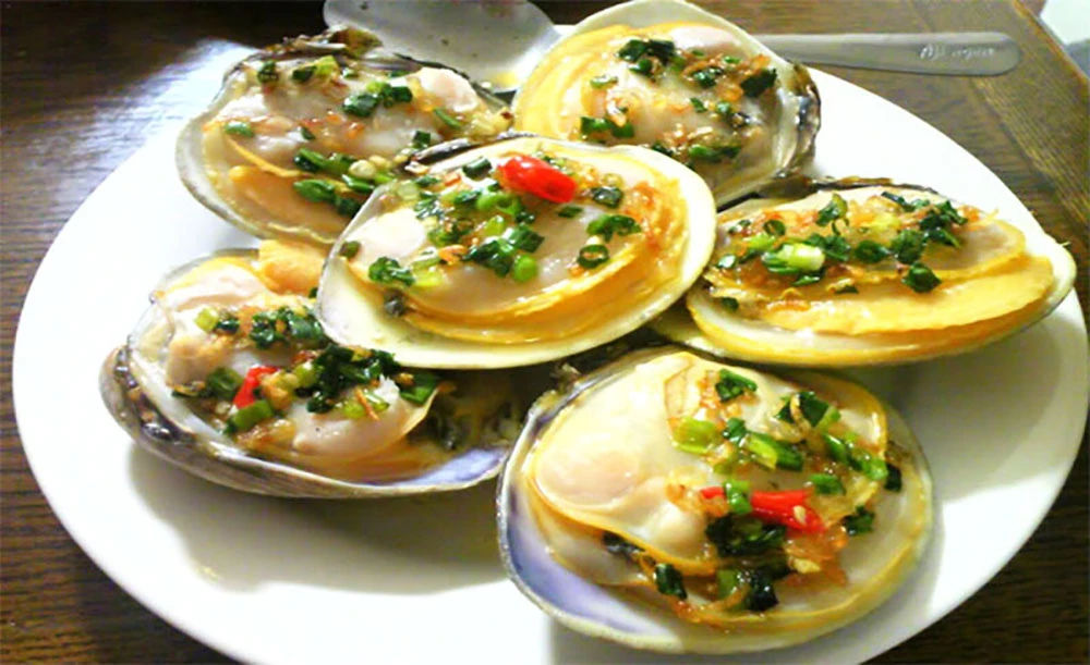 A plate of buttery grilled Ngán with scallions and chili, presented on white porcelain