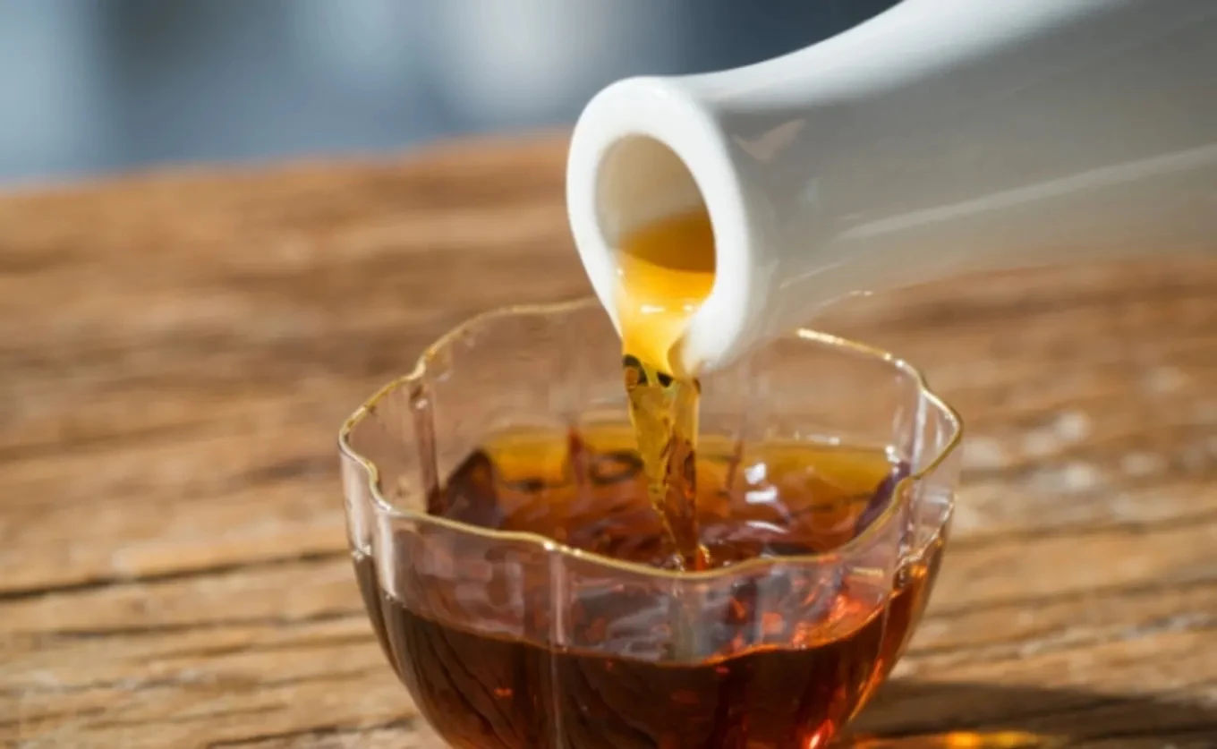 Rượu nếp ngâm Hoành Bồ màu hổ phách rót ra ly thủy tinh trên bàn gỗ