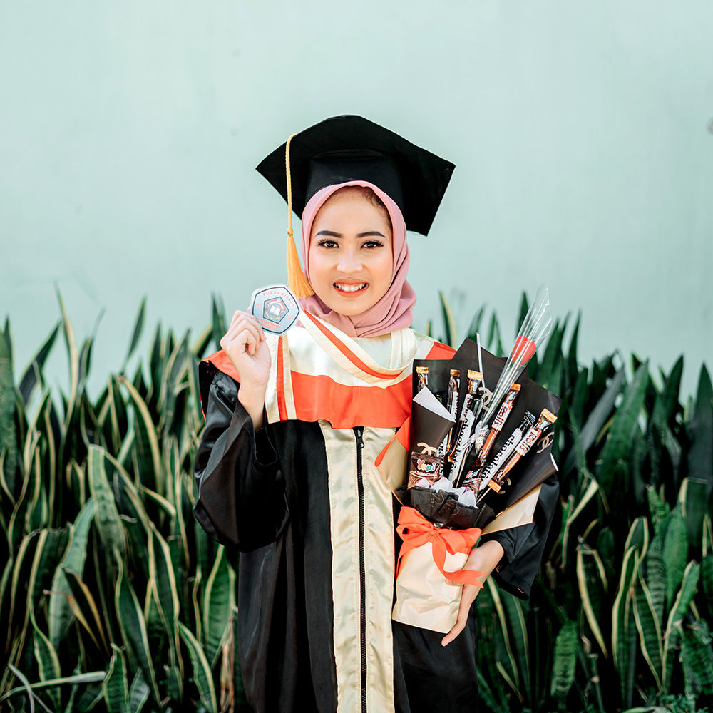 Graduate student walking across stage during formal convocation ceremony wearing black academic gown and mortarboard cap with proud expression receiving diploma