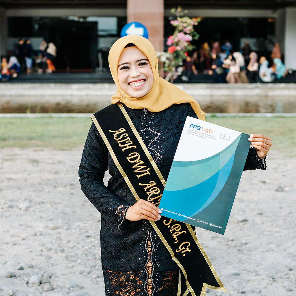 Graduate posing confidently in full academic dress with tassel hanging from mortarboard standing in front of historic university library building with stone columns