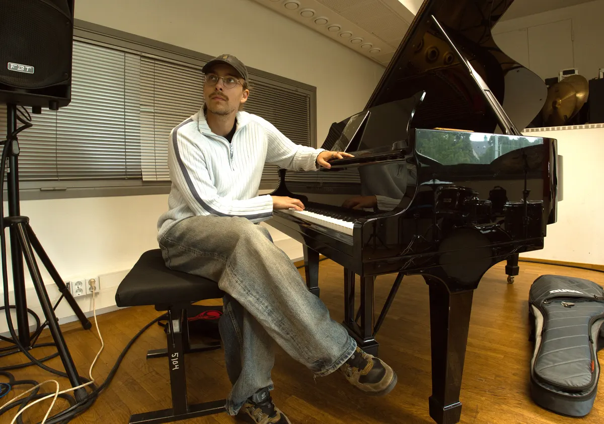 Pianisti flyygelin ääressä harjoituksissa, rumpusetti heijastuu flyygelin kannesta