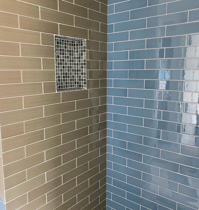 Custom shower with beige and blue subway tile and mosaic niche in Burnet, Texas