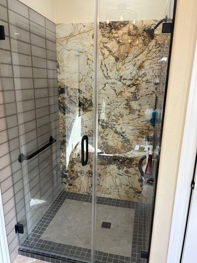 Modern shower remodel with marble accent wall and black trim glass door in Burnet, Texas