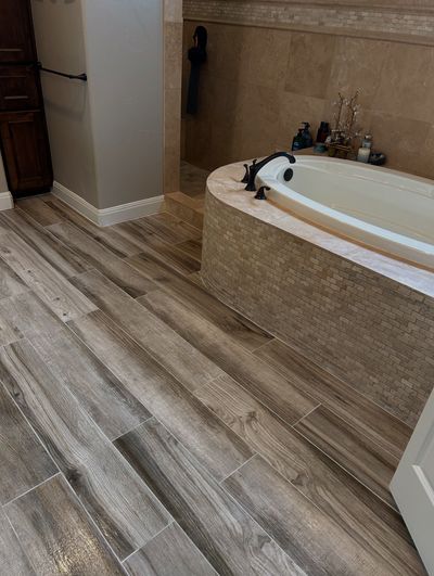 Bathroom remodel with wood-look tile flooring and built-in soaking tub in Cedar Park, Texas