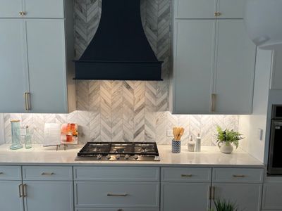 Modern kitchen backsplash with chevron marble tile and custom vent hood in Leander, Texas
