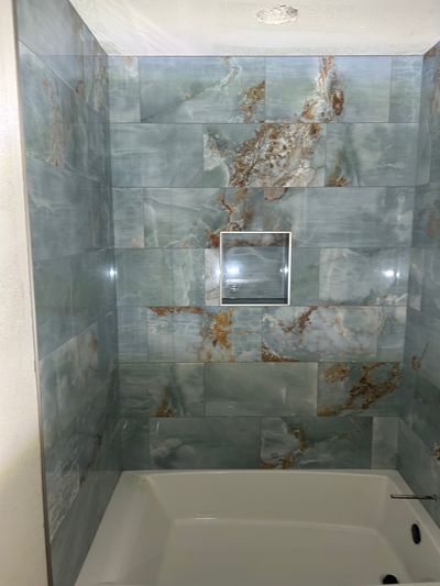 Luxury bathtub surround with blue-gray marble tile and niche in Marble Falls, Texas
