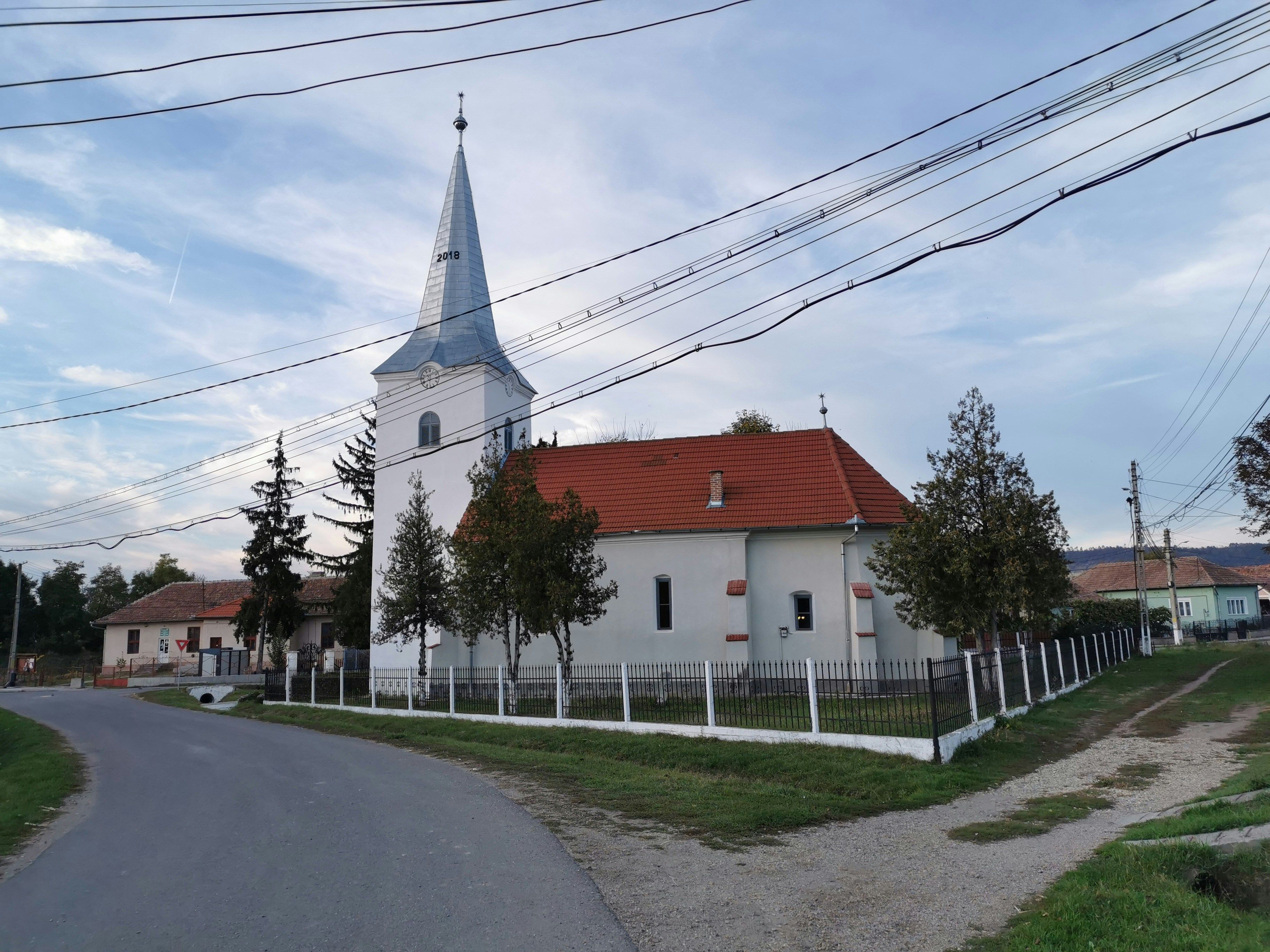 white and red concrete house near road under white clouds during daytime