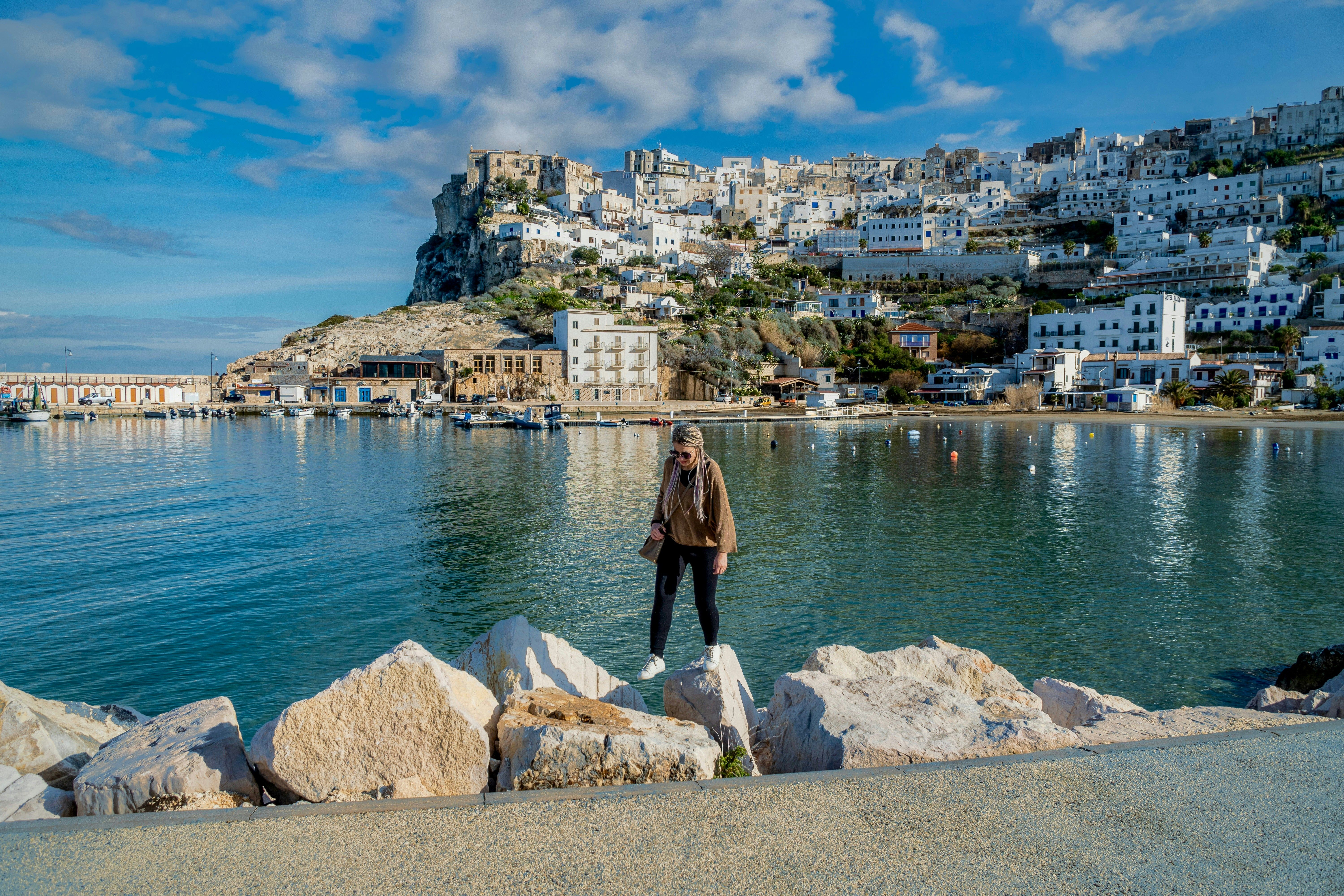 a man standing on a rock next to a body of water
