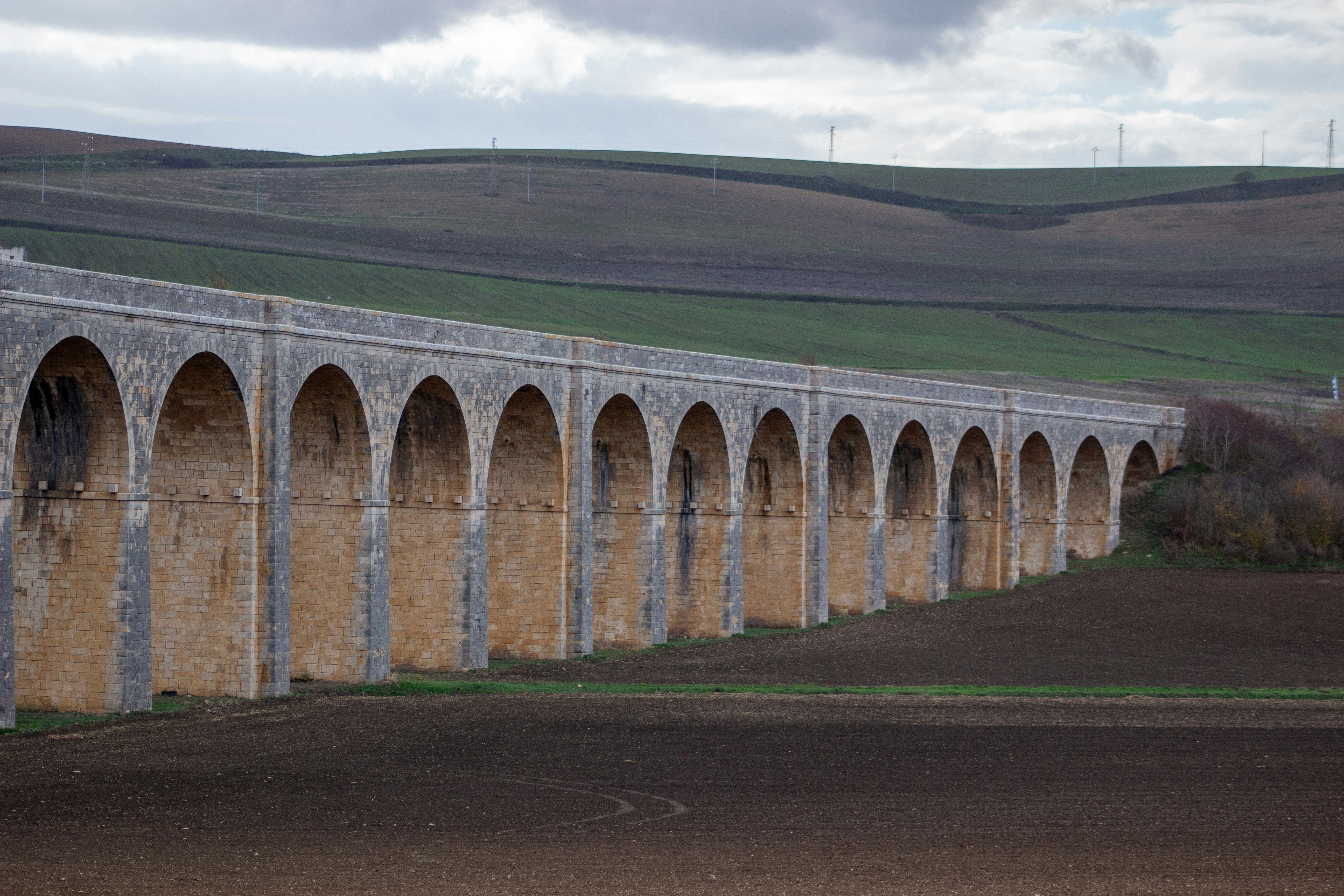 A large stone bridge with arches in the middle of a field