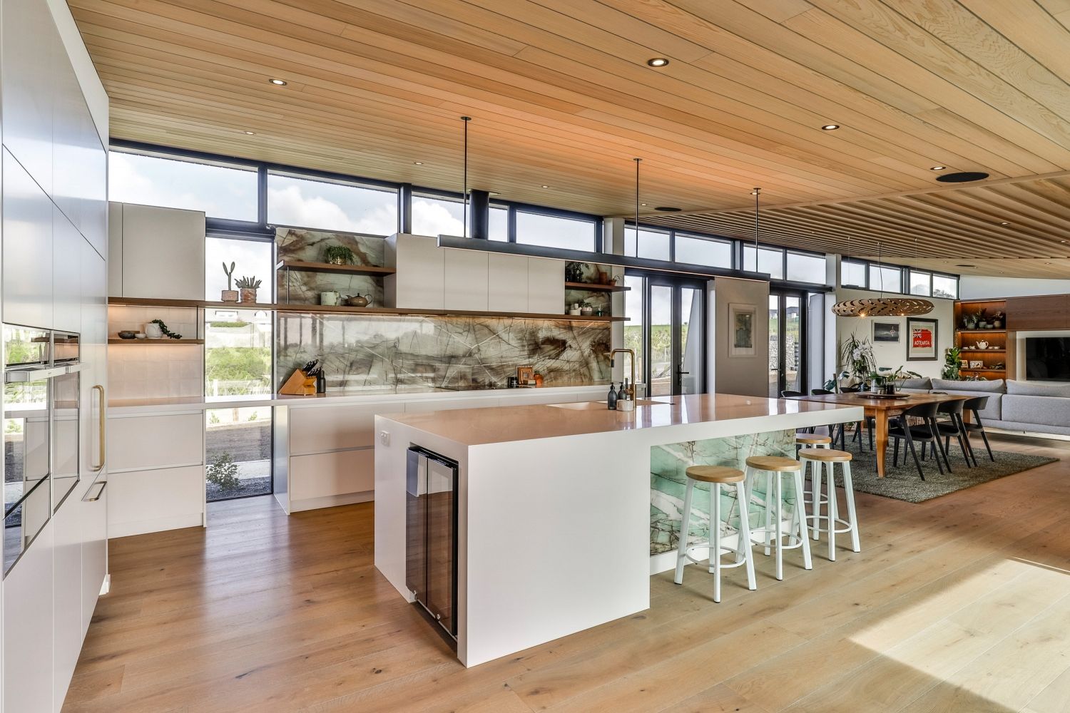 Open-plan kitchen and living area with natural palette and bespoke design elements, in Pukekohe..