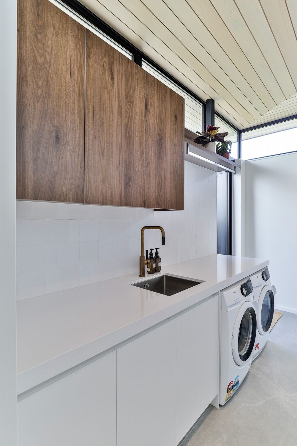 Laundry space featuring Corian benchtops and contrasting timber grain overheads in Pukekohe.
