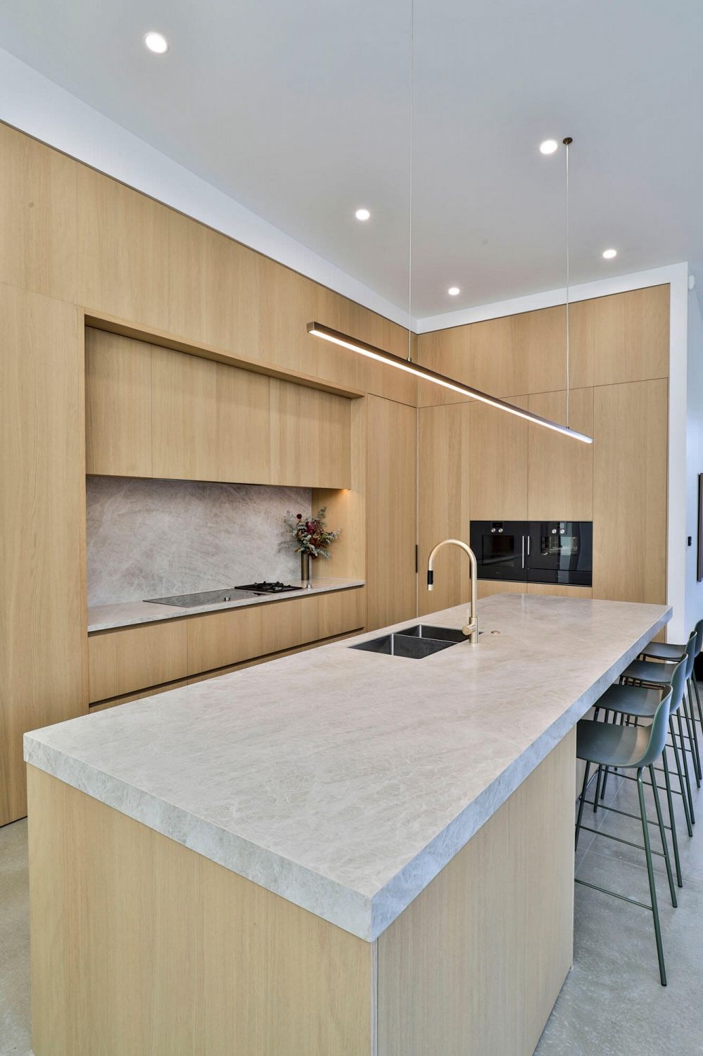 Open-plan kitchen with central island and seamless timber veneer cabinetry