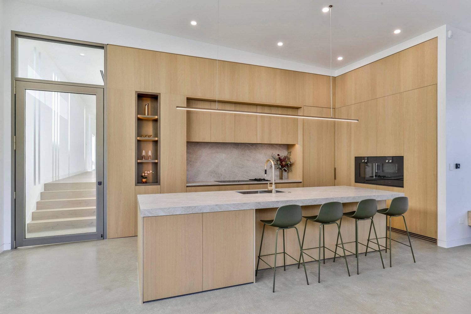 Architectural kitchen with handle-less joinery and continuous timber surfaces