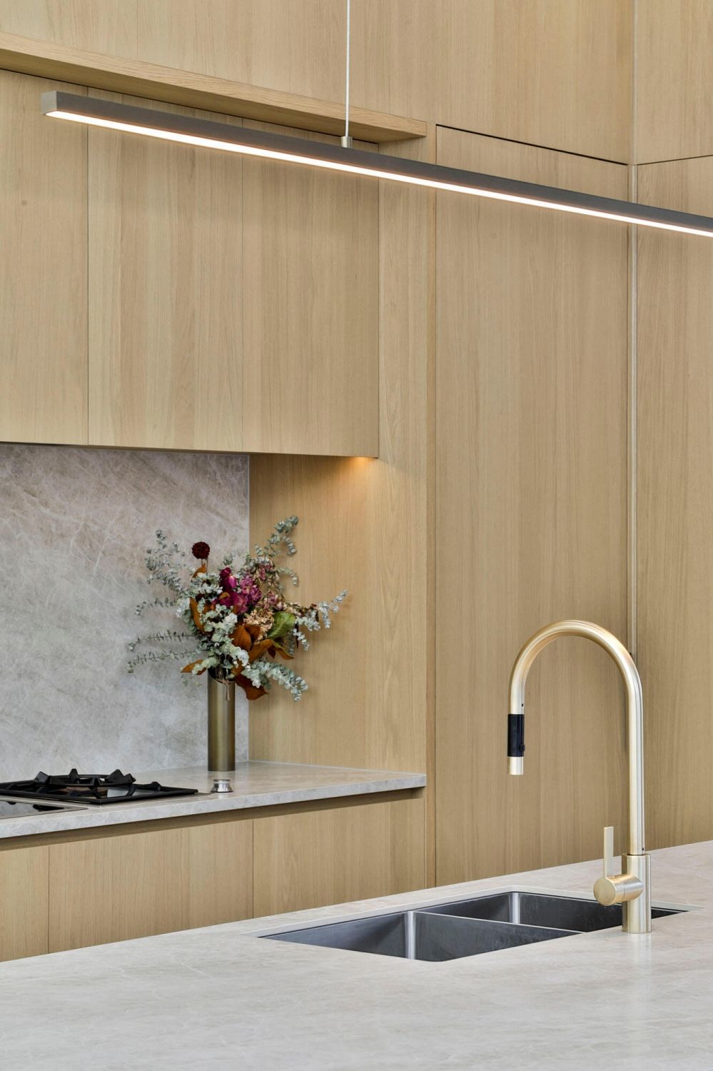 Kitchen sink detail with brass tapware and seamless stone surround