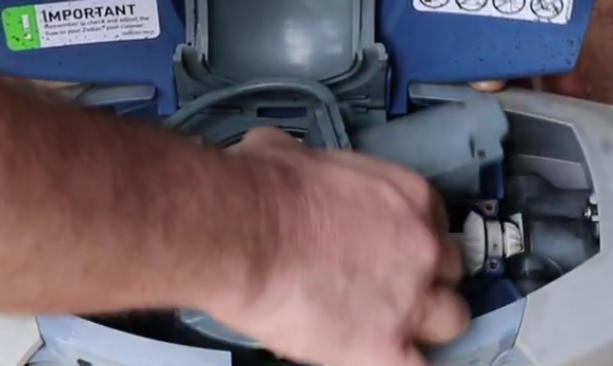Screenshot 2026-04-16 103357 Am - Diy Pool Resources - Inyopools.com Close-up of a person's hand working on a blue power tool or motor, with components exposed and a warning label visible on the unit.