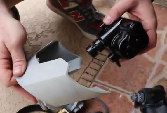 Screenshot 2026-04-23 94554 Am - Diy Pool Resources - Inyopools.com Person holds a gray plastic component next to a small black engine part, as if assembling a model vehicle or RC gadget.